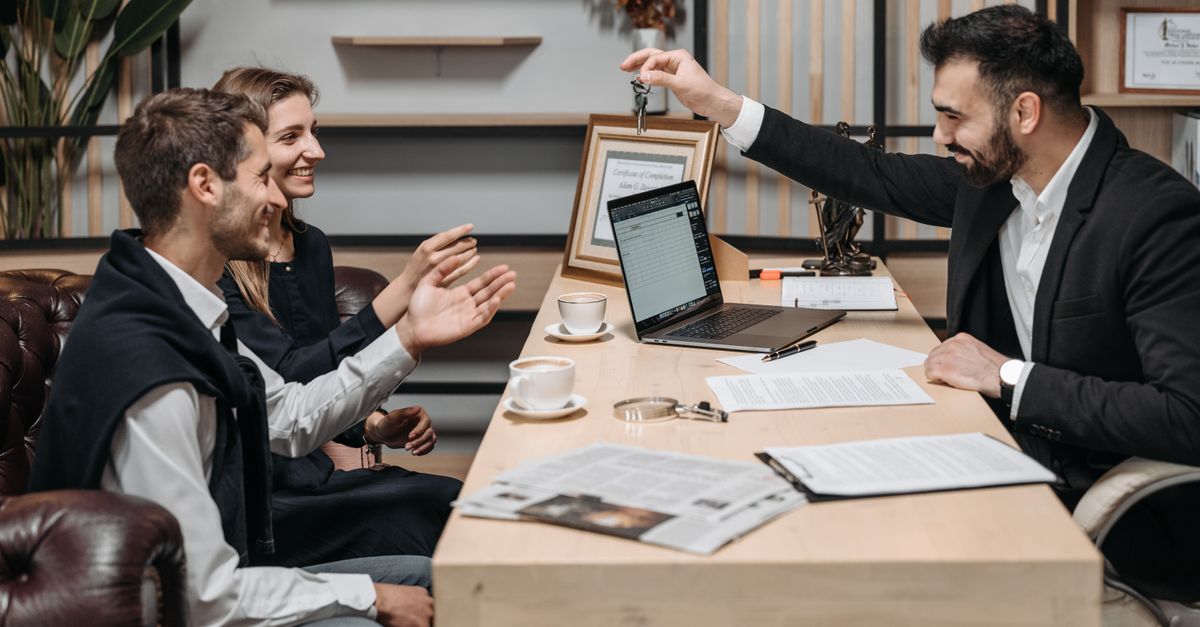 A property agent meeting a couple of buyers at an office table with a laptop