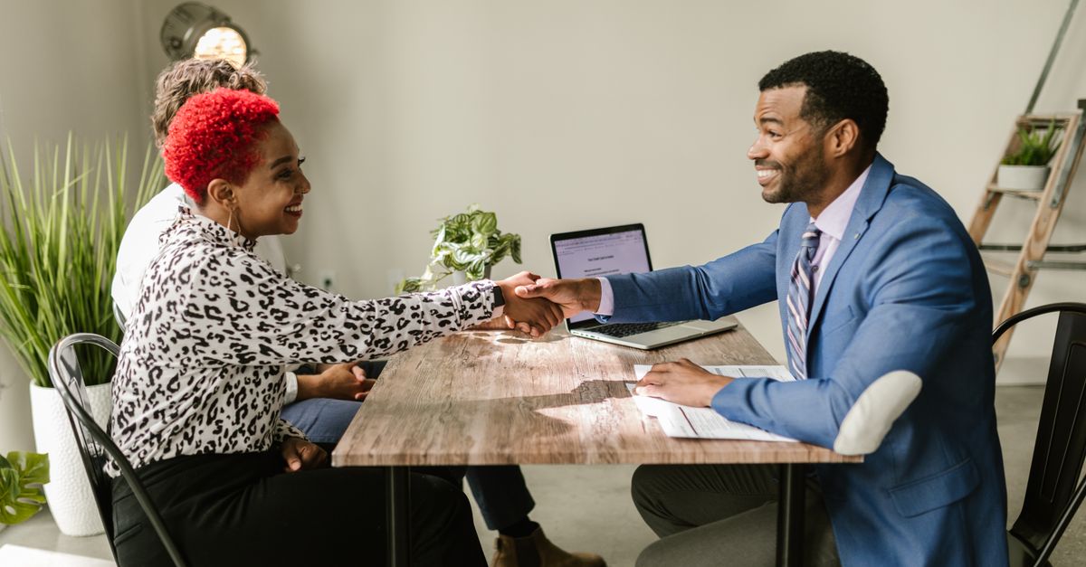A client shaking hands with a bank adviser across a desk