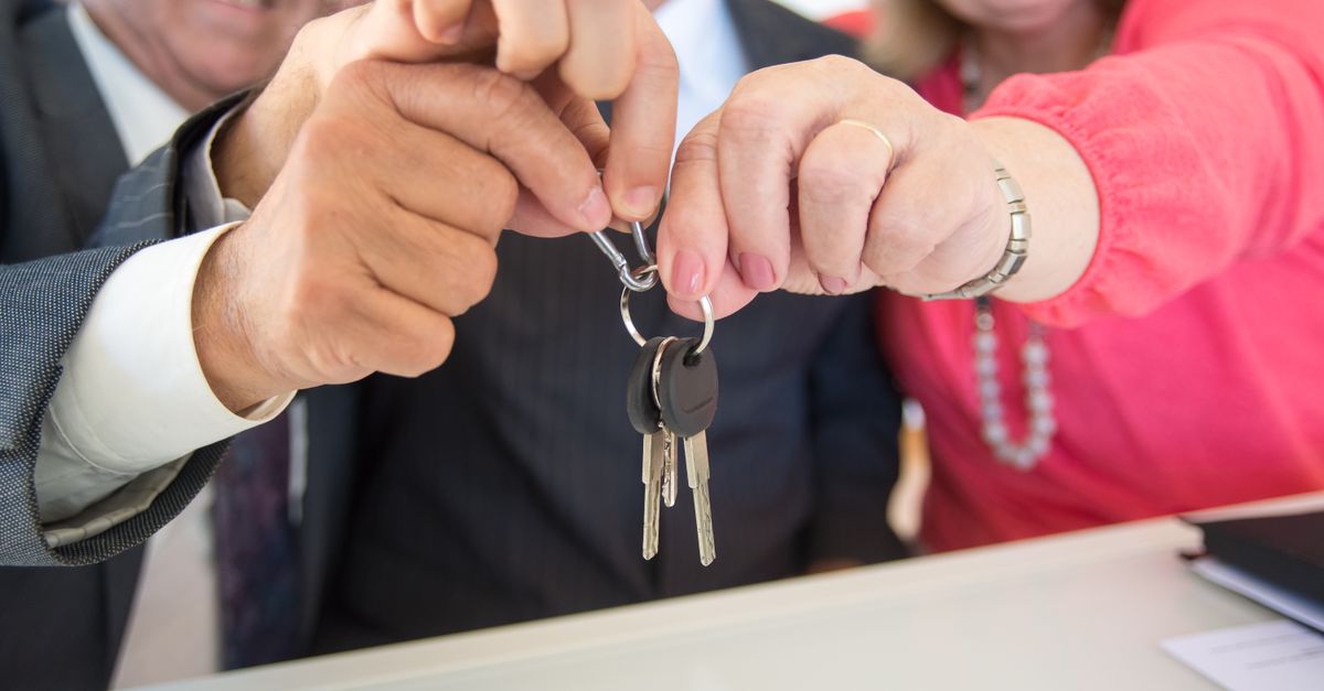 Two buyers smiling as they hold up the keys to their new property