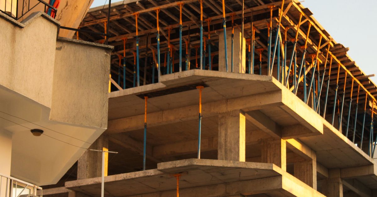 A concrete building frame under construction lit by warm sunset light