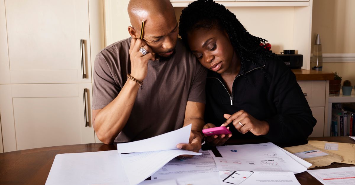 A couple reviewing paperwork and bills together at a kitchen table