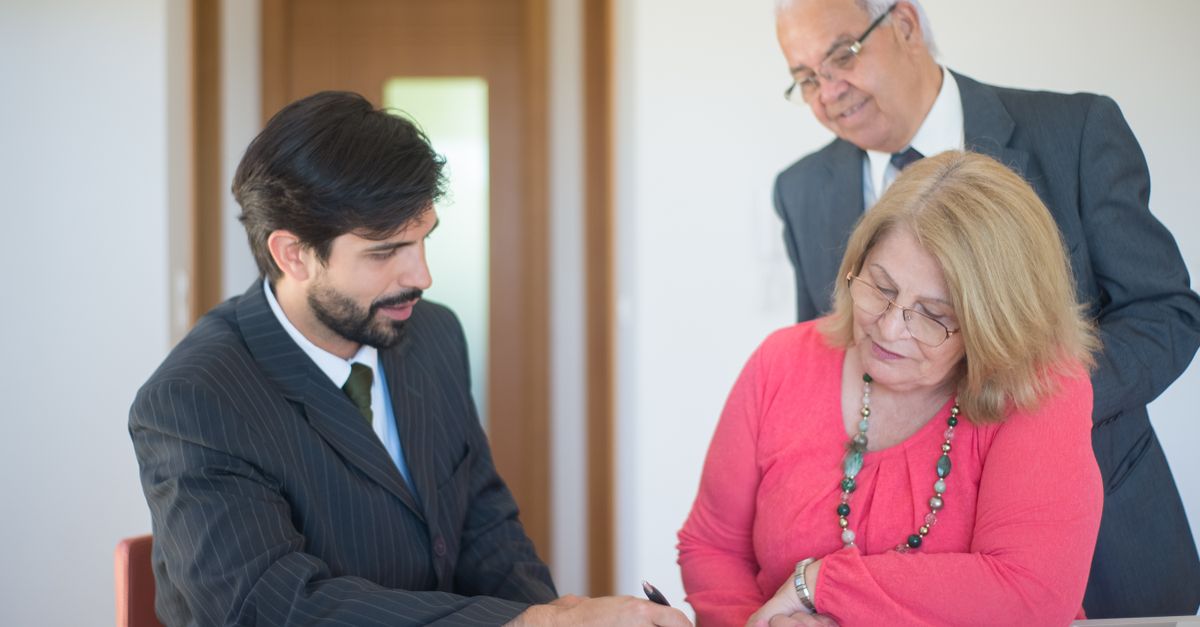 A couple signing documents with an adviser in an office