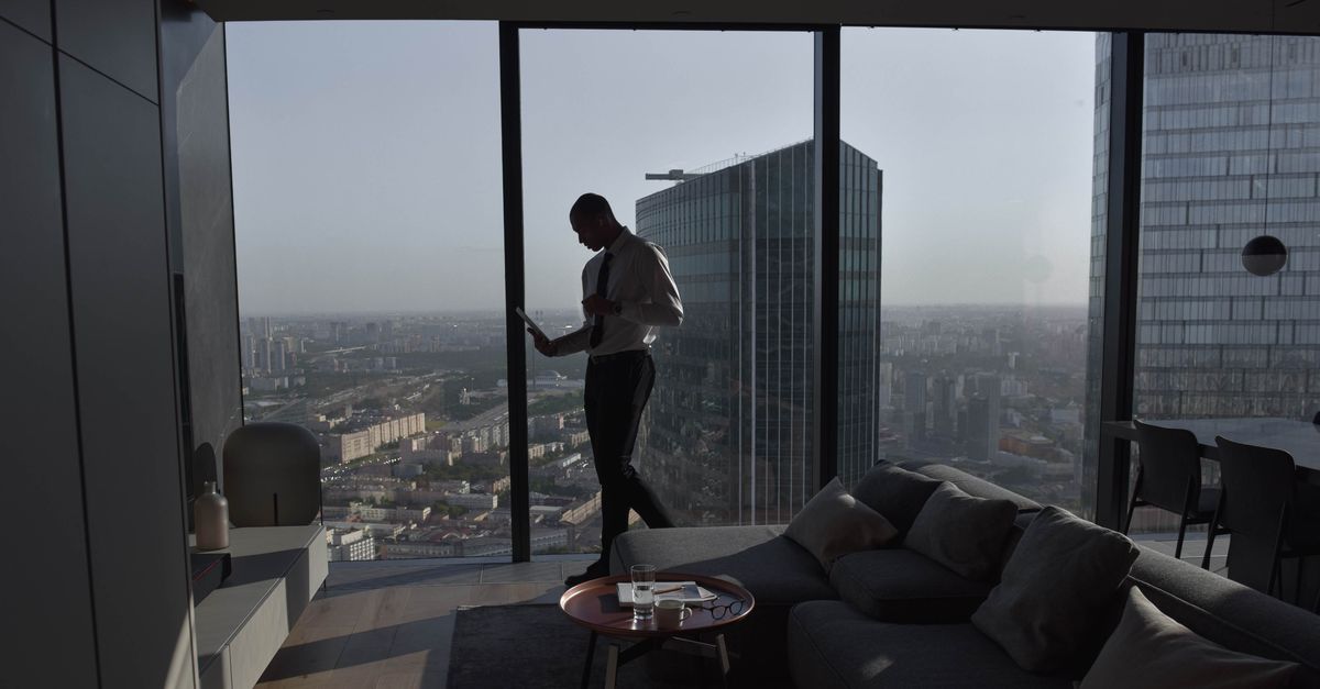 A silhouetted figure looking out over the city from a high-rise apartment