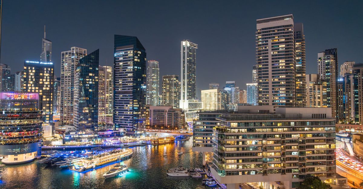 Dubai Marina apartment towers reflected in the marina at night