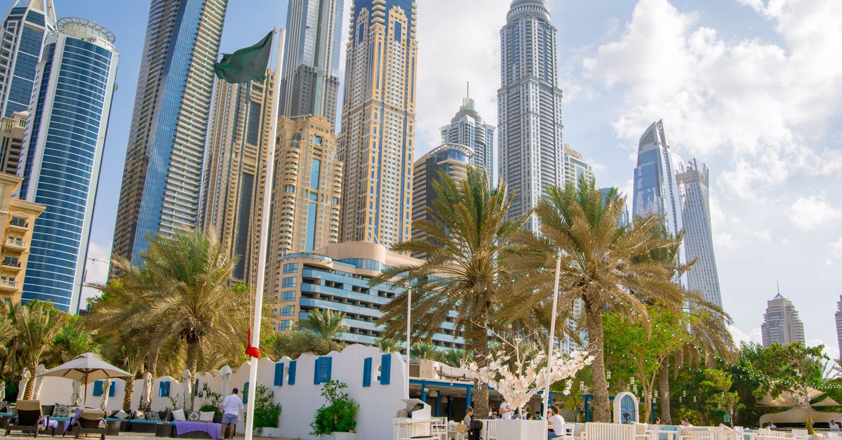 Street-level view of Dubai Marina towers framed by palm trees