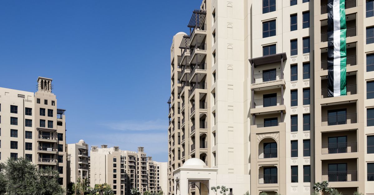 A mid-rise residential apartment building in Dubai with a UAE flag on its facade