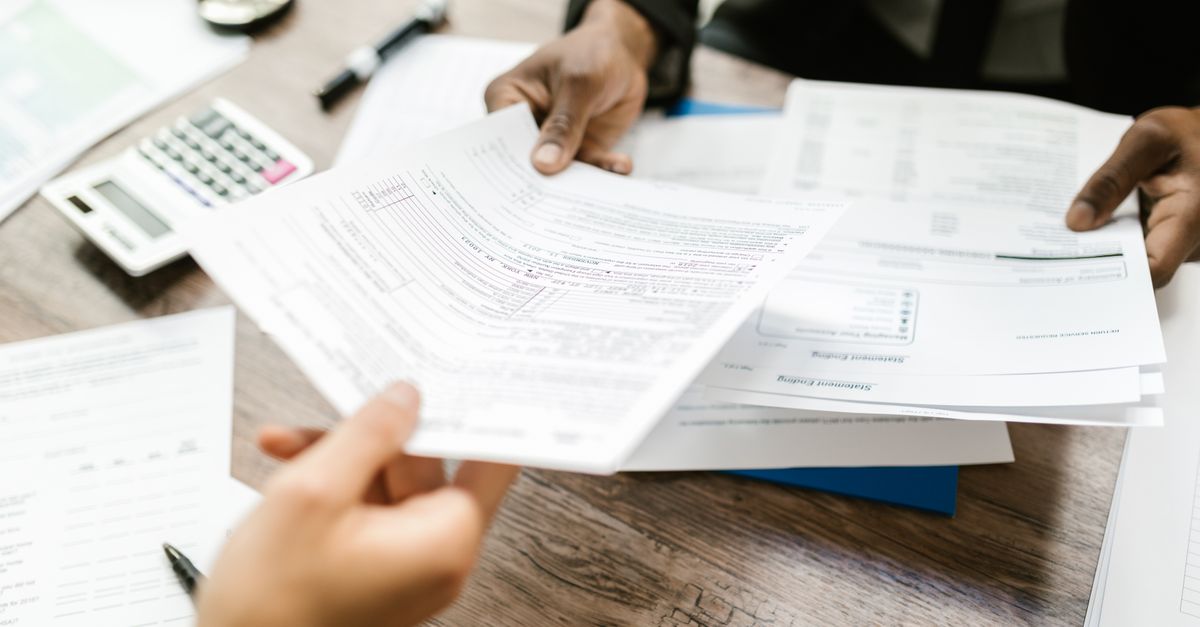 Two people exchanging documents across an office desk