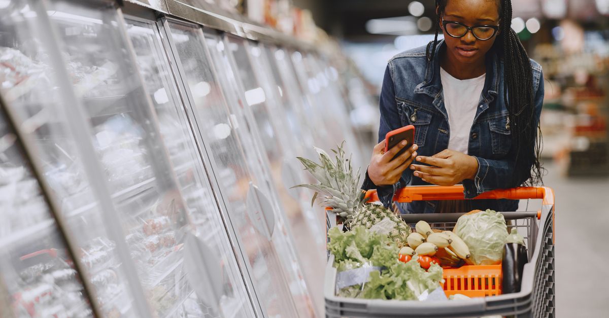 A shopper choosing groceries with a trolley in a supermarket