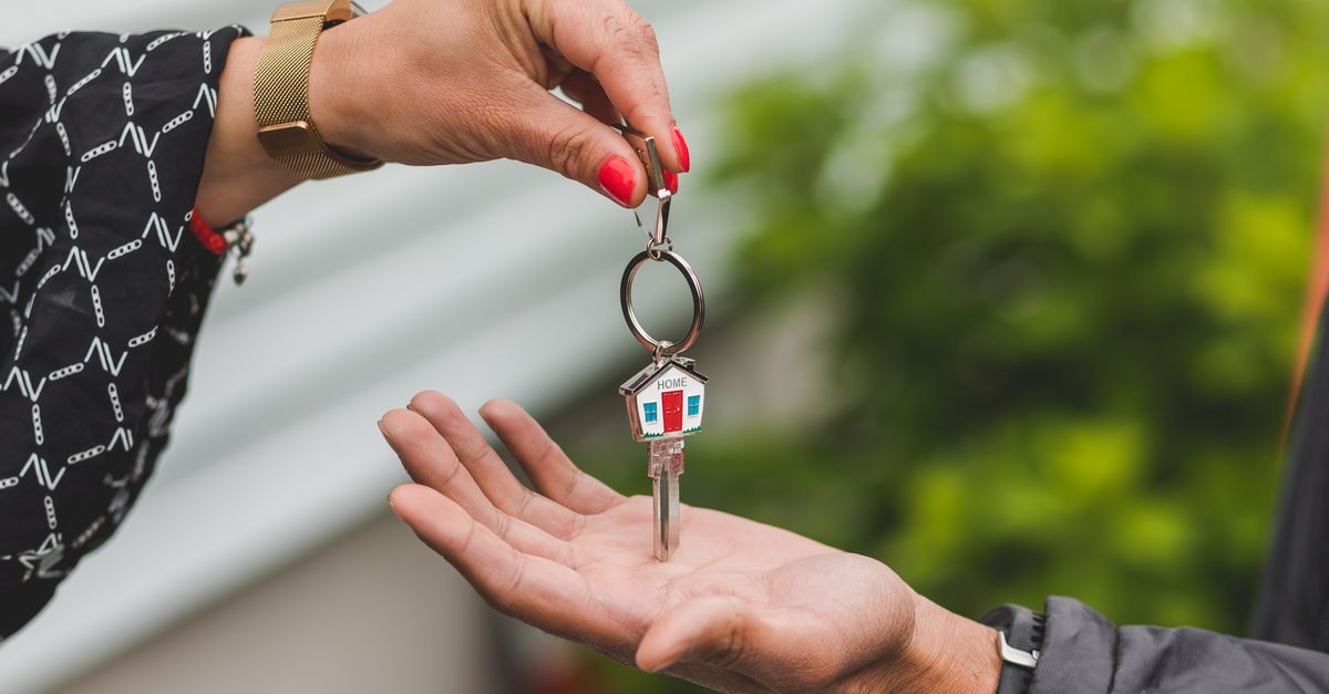 Oqood vs Title Deed in Dubai: What You Actually Own and When 1 A hand passing a house key with a house-shaped keychain to another person