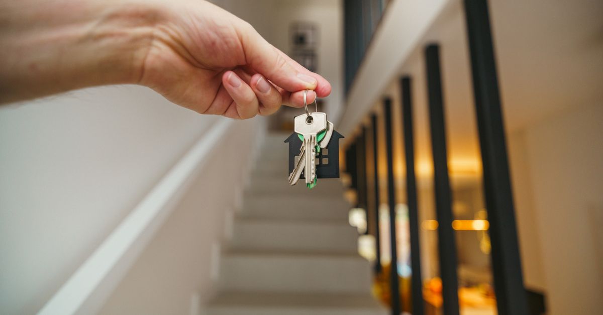 A hand holding house keys inside a bright modern home