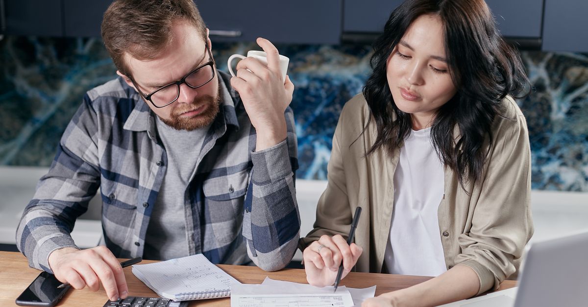 A couple reviewing household bills with a calculator and a laptop