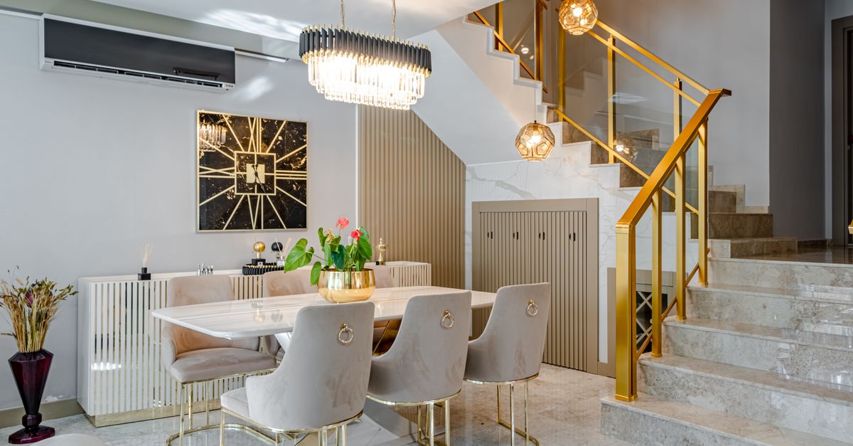 A modern dining room with a marble table, gold accents and statement lighting