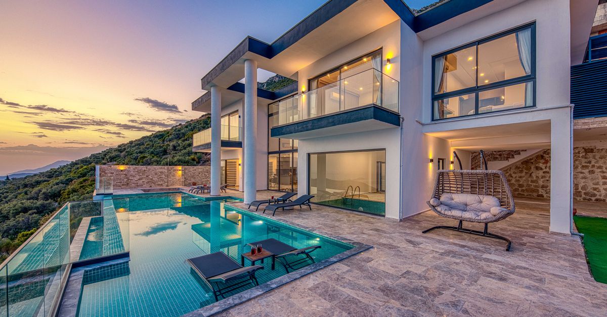 A modern two-storey villa with a swimming pool at dusk