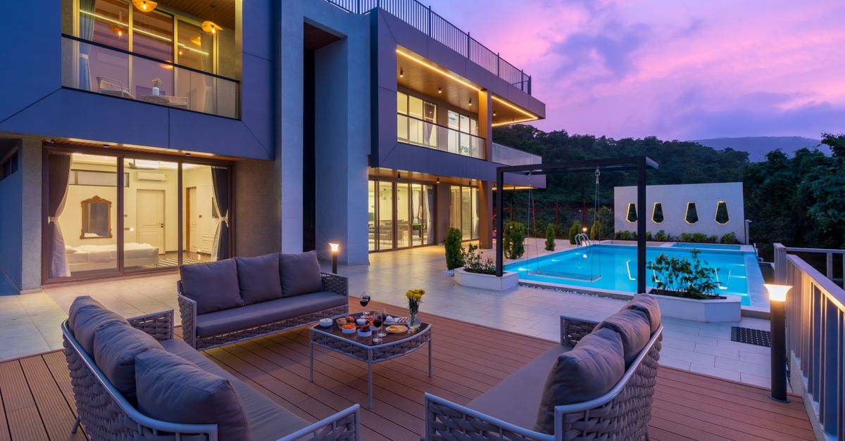 A contemporary villa with an outdoor terrace and swimming pool photographed at dusk