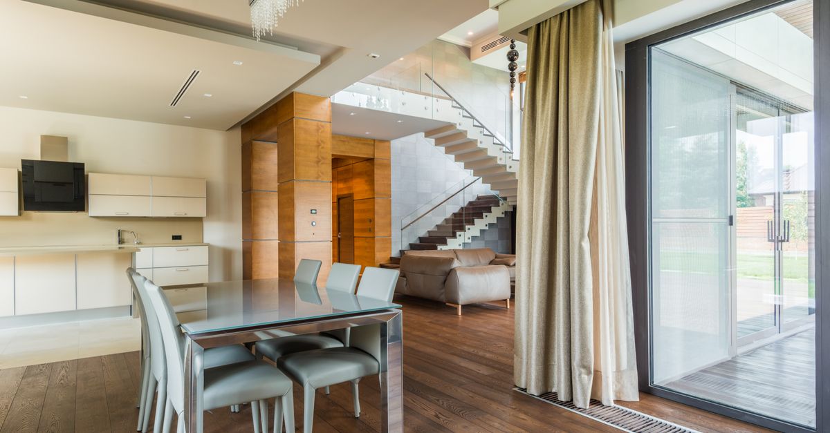 An open-plan dining and living area with a staircase and full-height glazing