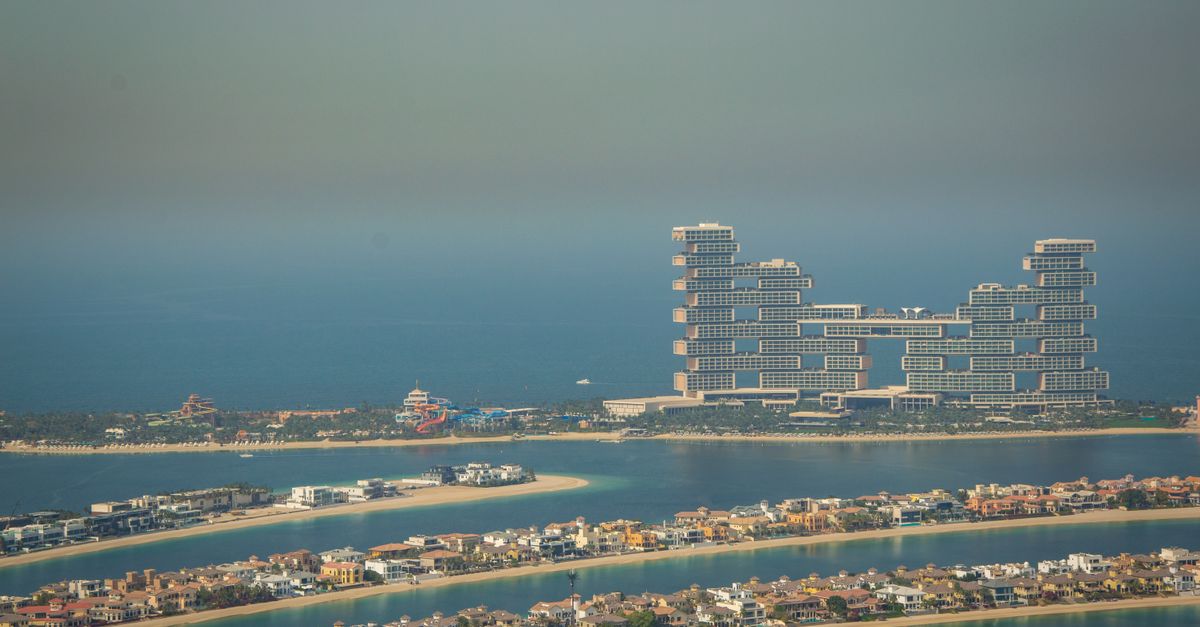 Rows of villas along the fronds of Palm Jumeirah with towers on the crescent behind