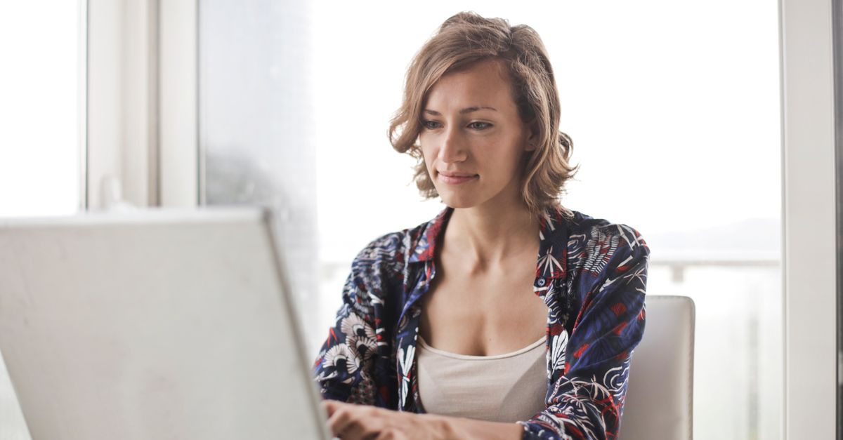 A professional working on a laptop in a bright home office