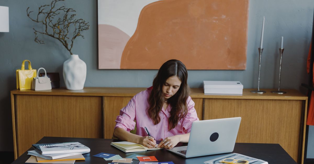 A remote worker at a home office desk with a laptop and colour swatches