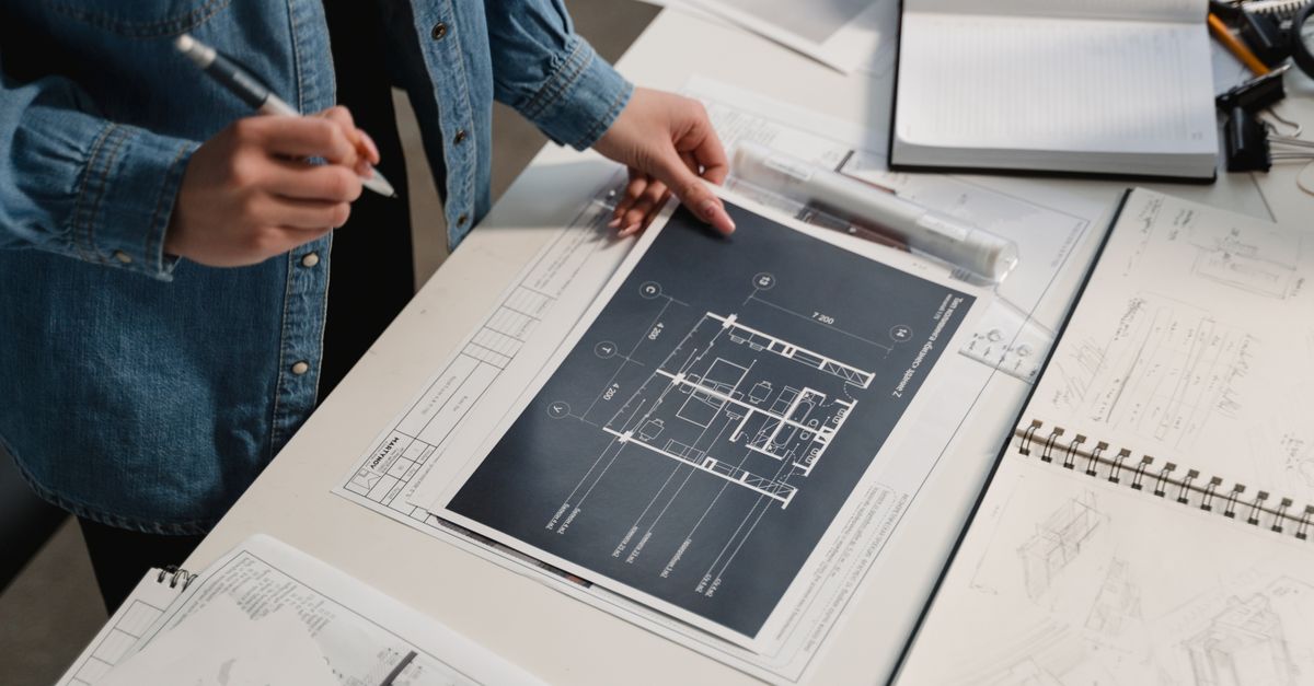Two people reviewing architectural blueprints on a desk