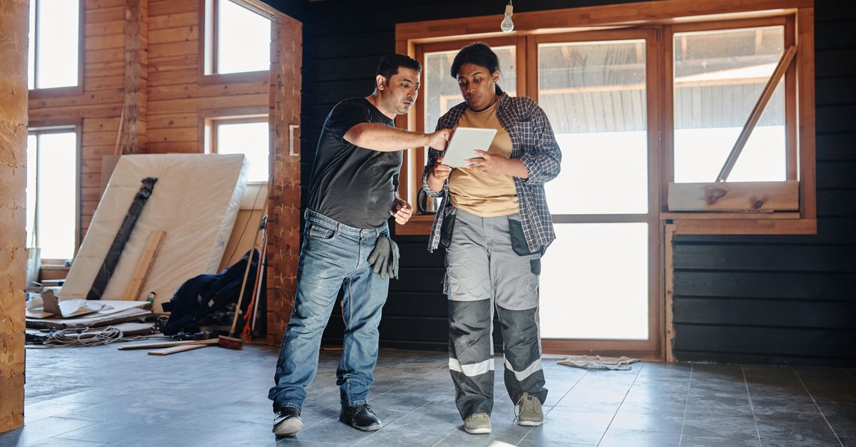 Two workers reviewing plans inside an unfinished building