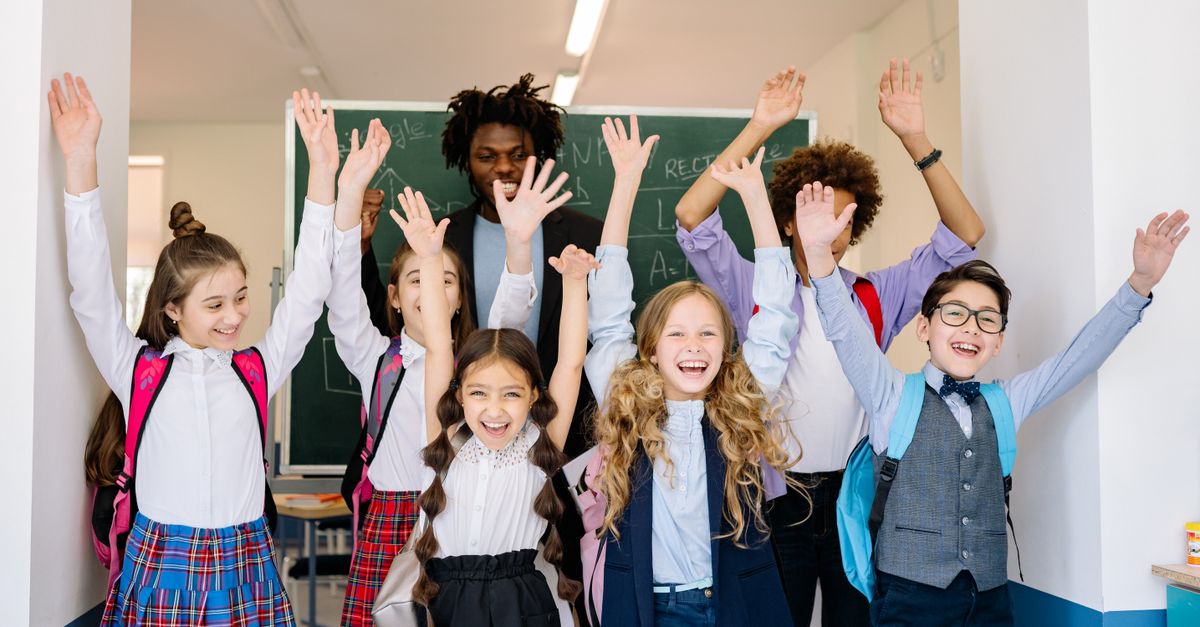 School children raising their hands in a bright classroom