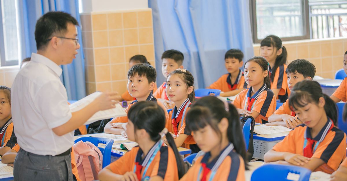 A teacher leading a lesson in a bright classroom of attentive pupils