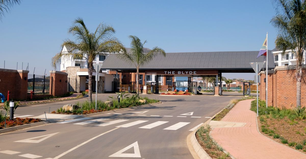The landscaped entrance to a gated residential community lined with palms