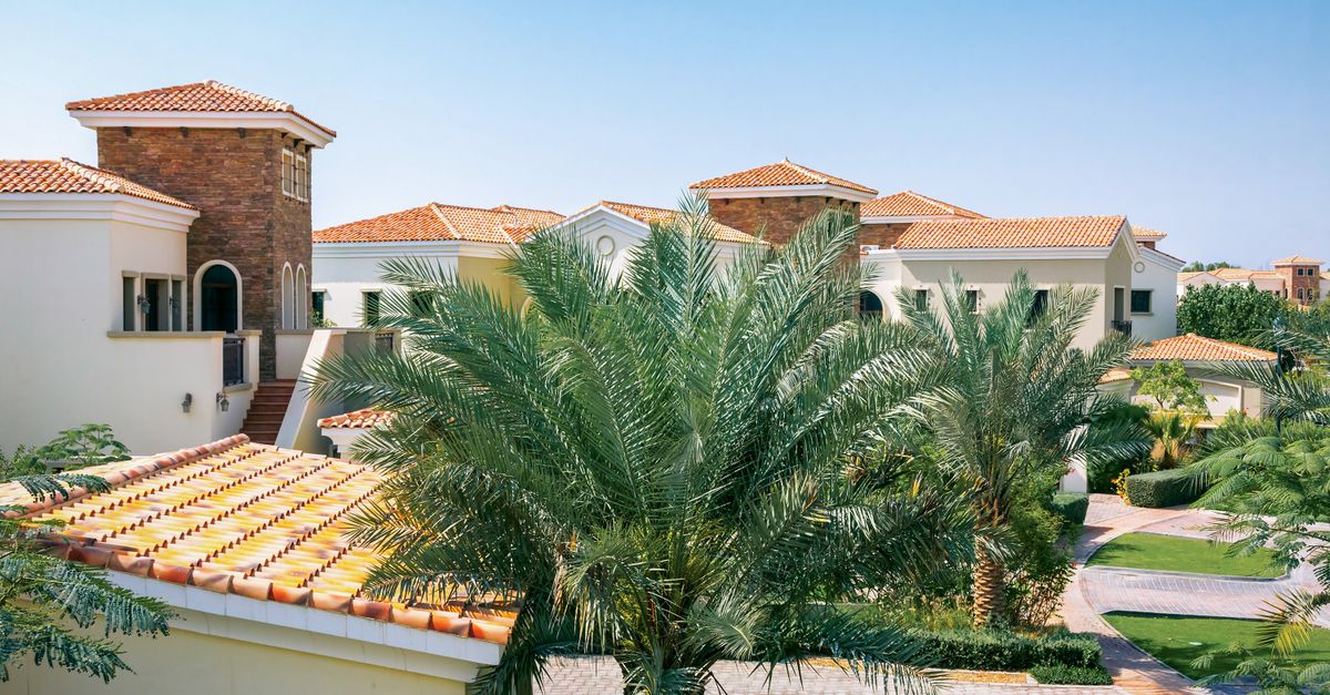 Villas with tiled roofs surrounded by mature palm trees