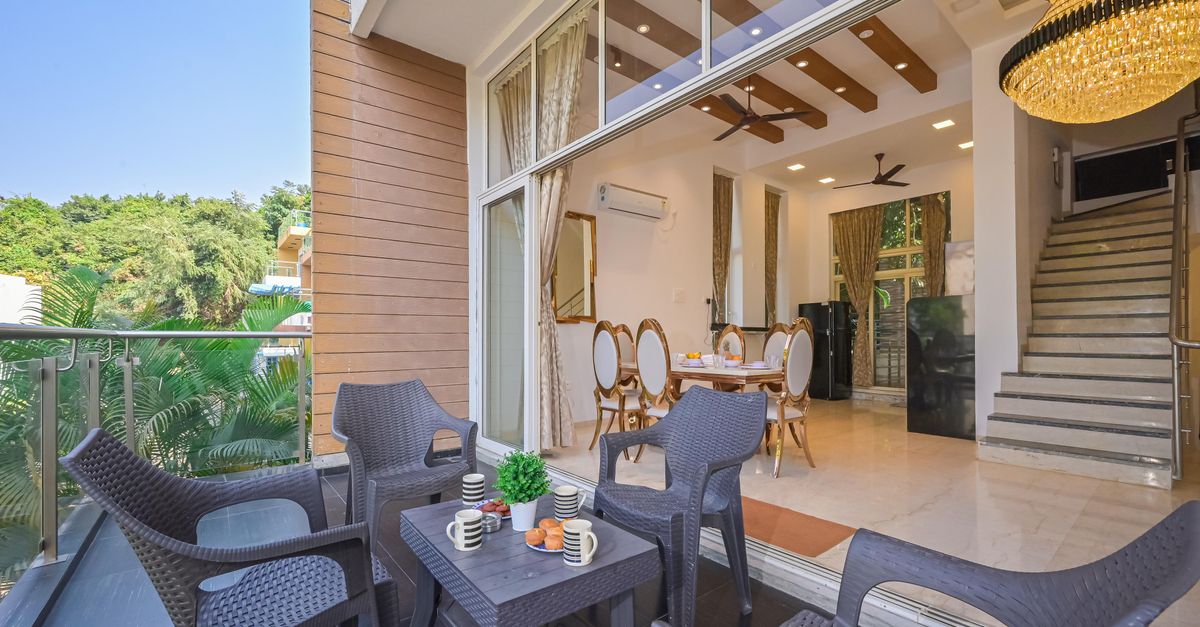 An indoor-outdoor living space with dining and lounge seating framed by greenery