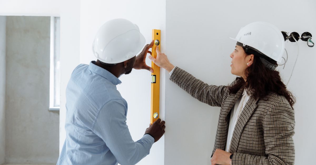 Two inspectors checking a wall with a spirit level inside a newly built home